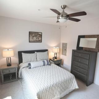 A modern bedroom with a neatly made bed, nightstands, and a dresser, featuring neutral tones and stylish decor.