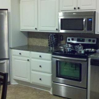 A modern kitchen featuring stainless steel appliances and white cabinetry.