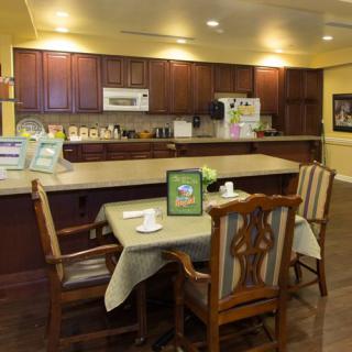 A cozy kitchen and dining area featuring wooden cabinets, a small table with chairs, and modern appliances.