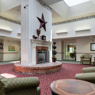 A cozy lobby interior with a central fireplace and seating area under a skylight.