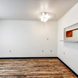 A minimalist empty room with white walls and a wooden floor.
