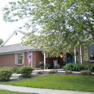 A suburban brick house with a porch and landscaped front yard.