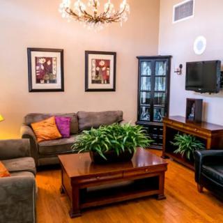 A cozy living room with sofas, a coffee table, artwork on the walls, and a television mounted above a cabinet.