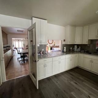 A modern kitchen with white cabinets and open access to a dining area.