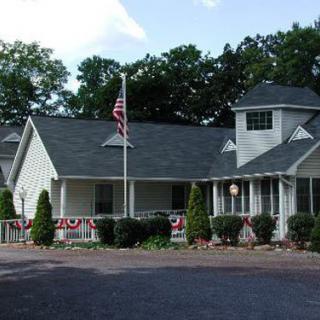 A residential building with an American flag in the front and trees in the background.