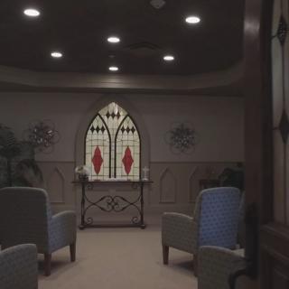 A serene chapel interior with stained glass and comfortable seating.