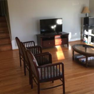 A cozy living room with a TV, chairs, and a coffee table on hardwood flooring.