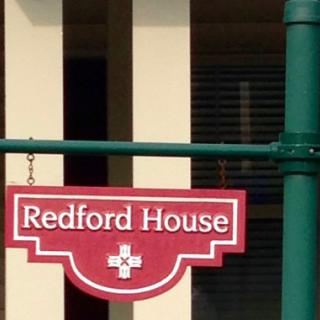 A red and white sign for 'Redford House' hanging outside a building.