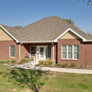 A brick residential house with a front yard and peaked roof.