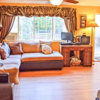 A cozy living room with a large sofa, computer desk, and ample natural light from the window.