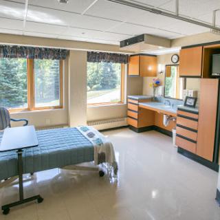 A modern hospital patient room with a bed, window, and essential furnishings.
