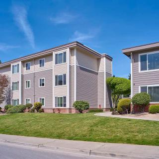 A residential apartment building with well-maintained landscaping under a clear blue sky.