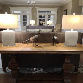 A cozy living room with a wooden table adorned with decorative birds and lamps.