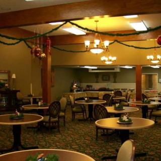 A warmly lit dining room with decorated ceilings and multiple tables and chairs.