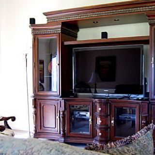 A wooden entertainment center in the living room, featuring a television and speakers.