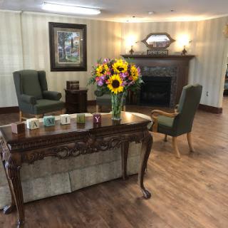 A cozy living room setting featuring elegant furniture and a vibrant bouquet of sunflowers.