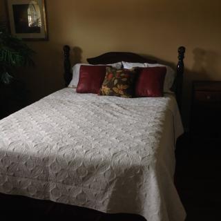 A cozy bedroom with a neatly made bed featuring decorative pillows and a quilt.