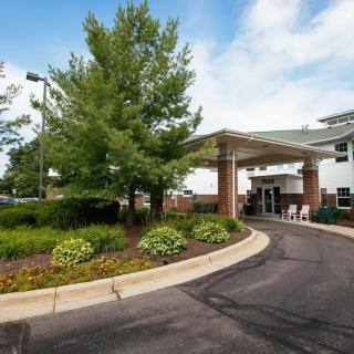 A building entrance with a driveway and landscaped surroundings.