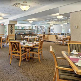 An empty dining area with neatly set tables and chairs, featuring warm lighting.