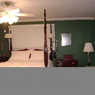 A traditional bedroom with a four-poster bed, green walls, and classic furnishings.