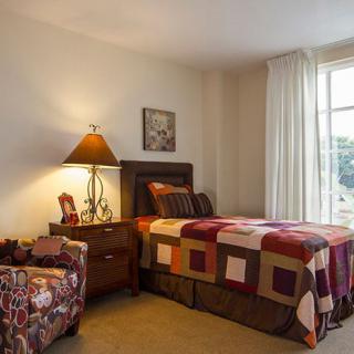 A cozy bedroom with a single bed, nightstand, and window with curtains.