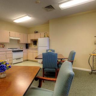 A cozy kitchen and dining area with tables, chairs, a refrigerator, and a stove.