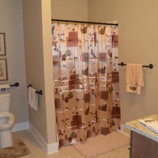 A cozy bathroom featuring a floral shower curtain, a toilet, and neatly hung towels.