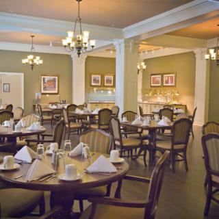 An elegantly set dining area with neatly arranged tables and chairs, complemented by chandeliers.