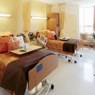 A clean and well-organized hospital room with two beds and medical equipment.