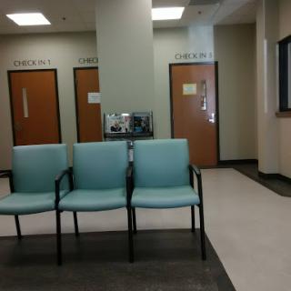 A waiting area in a medical facility with teal chairs and closed doors.