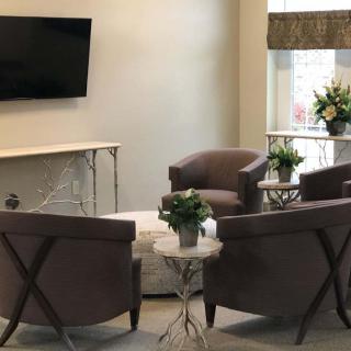 A modern living room with comfortable chairs, a television, and elegant floral arrangements.