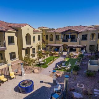 A well-maintained apartment complex with a landscaped courtyard featuring outdoor seating and a fire pit.