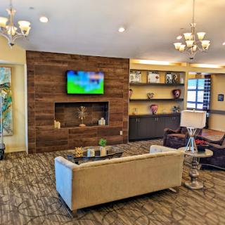 A modern living room showcasing stylish furniture and a television, complemented by warm lighting and elegant decor.