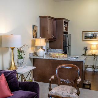 A cozy living room space with a view of the kitchen, featuring elegant furniture and warm lighting.