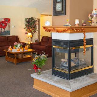 A cozy living room with a central fireplace and autumn-themed decor.