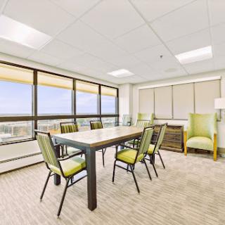A bright and modern conference room featuring a large table and comfortable seating with a view.