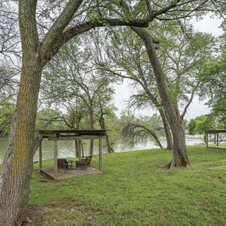 A peaceful park setting with trees and a gazebo by the river.