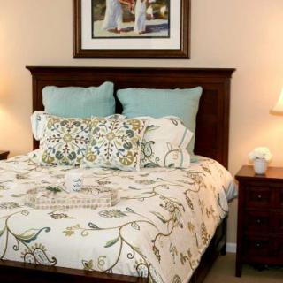 A cozy bedroom with a decorated bed and nightstands each holding a lamp.