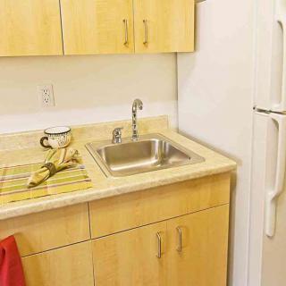 A compact kitchen area featuring a sink, countertop, and refrigerator.