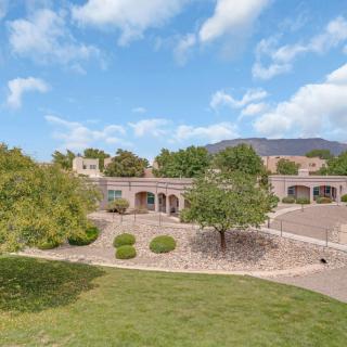 A scenic view of a house surrounded by a lush garden and under a cloudy sky.