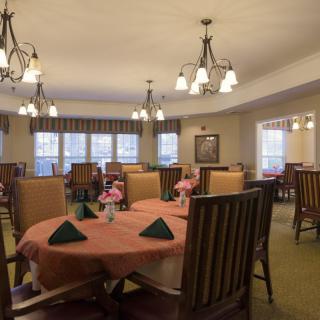 A cozy dining room with neatly arranged tables and elegant chandeliers.