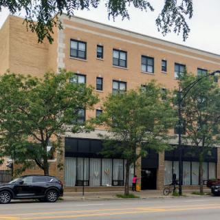 A view of a multi-story commercial building with trees lining the sidewalk.
