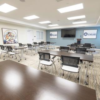 A modern conference room equipped with tables, chairs, and a presentation screen.