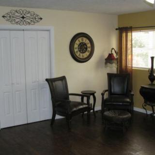 A cozy living room corner with two chairs and a decorative wall clock.
