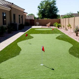 A backyard with a well-maintained artificial turf putting green.