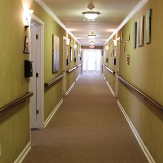 A well-lit hallway with carpeted flooring and multiple doors on either side.