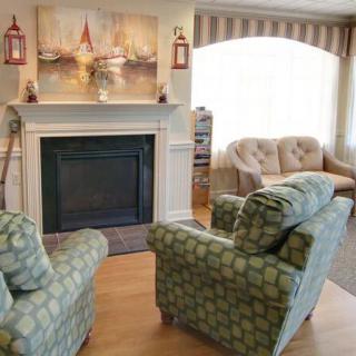 A cozy living room with patterned armchairs, a sofa, and a fireplace adorned with artwork.