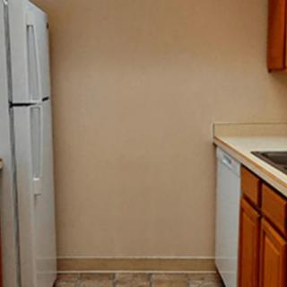 A small kitchen area featuring appliances and wooden cabinets.