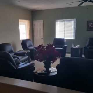 A cozy living room with leather chairs and a sofa arranged around a central coffee table.