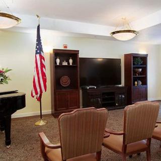 A cozy living room with a piano, television, and an American flag.